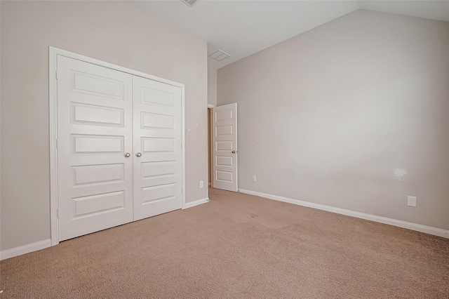 unfurnished bedroom with a closet, carpet flooring, and lofted ceiling