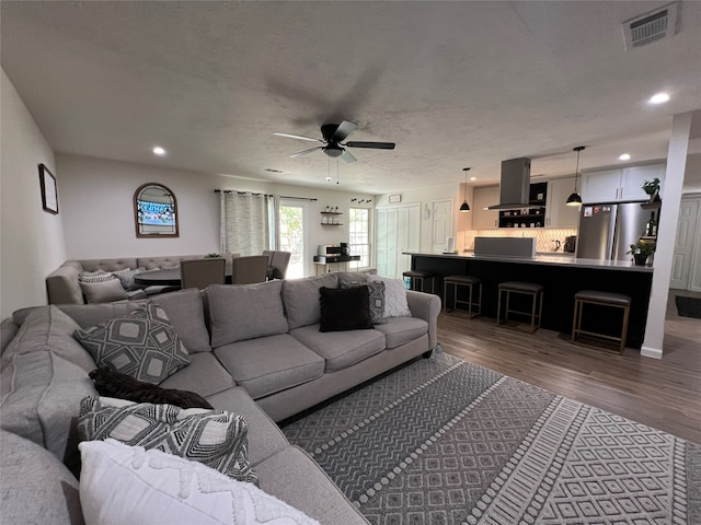 living room with ceiling fan, hardwood / wood-style flooring, and a textured ceiling