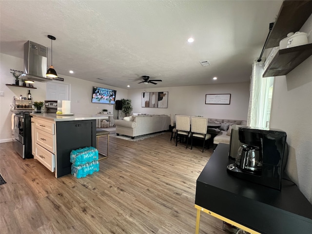 living room with a textured ceiling, light hardwood / wood-style floors, and ceiling fan