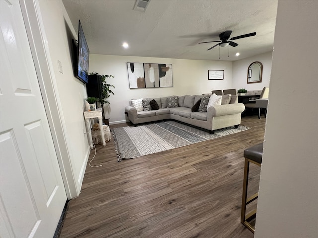 living room with ceiling fan, a textured ceiling, and dark hardwood / wood-style flooring