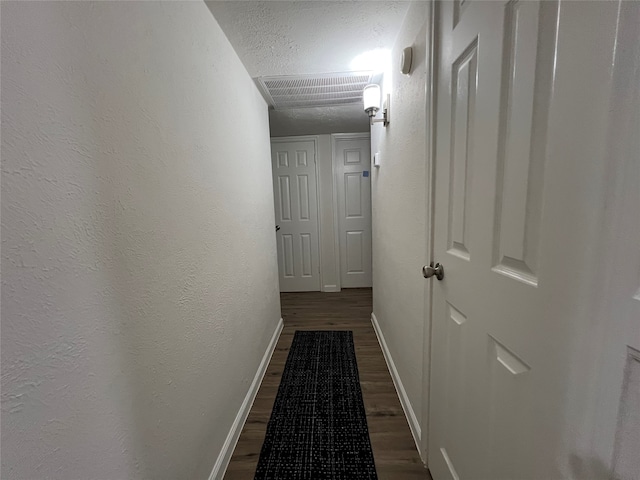 hall featuring a textured ceiling and dark hardwood / wood-style flooring