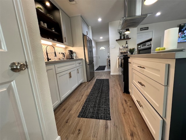 kitchen with hardwood / wood-style flooring, island range hood, stainless steel appliances, and white cabinets