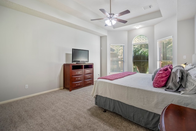 carpeted bedroom featuring a tray ceiling and ceiling fan