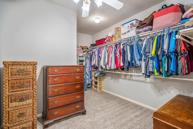 walk in closet with light colored carpet and ceiling fan