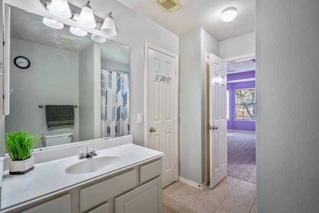 bathroom with tile patterned flooring, a textured ceiling, vanity, and toilet