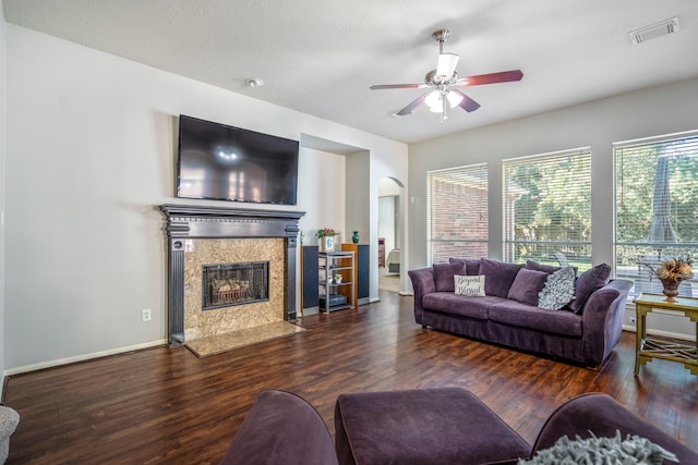 living room featuring a high end fireplace, ceiling fan, and dark wood-type flooring