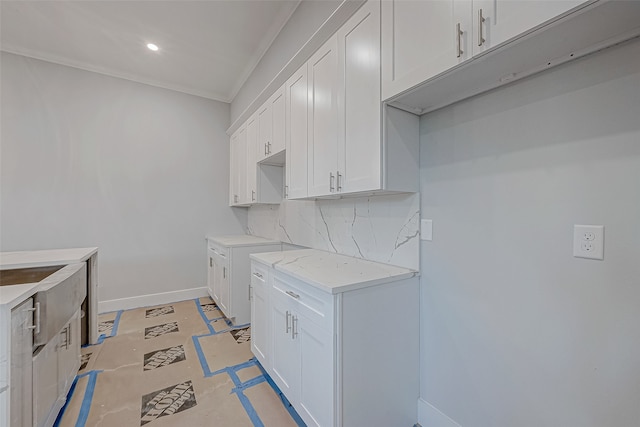 kitchen featuring tasteful backsplash, crown molding, and white cabinets