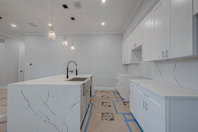 kitchen featuring sink, white cabinetry, tasteful backsplash, decorative light fixtures, and a kitchen island with sink