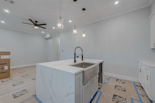 kitchen with crown molding, hanging light fixtures, a center island with sink, and white cabinets