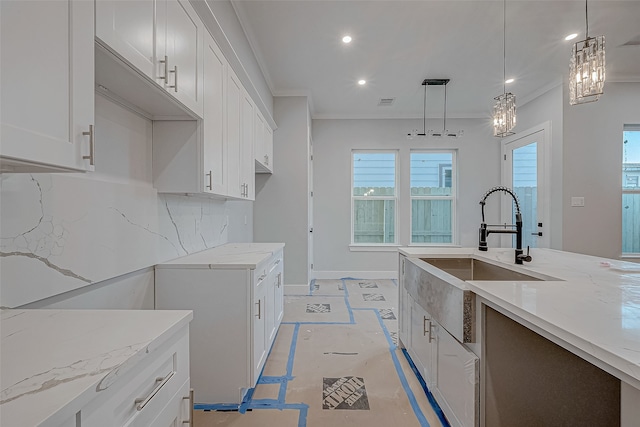 kitchen with sink, light stone counters, decorative light fixtures, decorative backsplash, and white cabinets