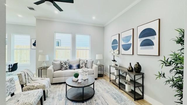 living area with crown molding, ceiling fan, and light hardwood / wood-style flooring