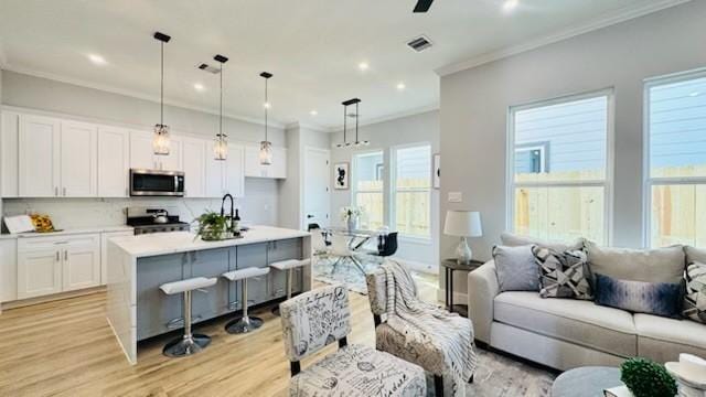 living room with crown molding, sink, ceiling fan, and light hardwood / wood-style floors