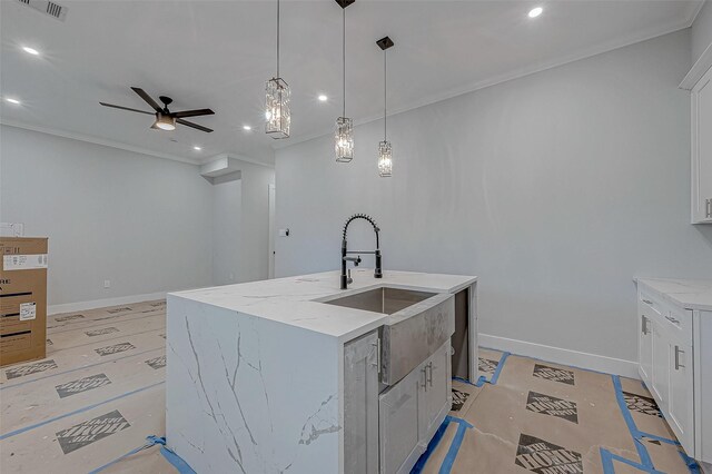 kitchen featuring white cabinets, pendant lighting, ornamental molding, and a kitchen island with sink