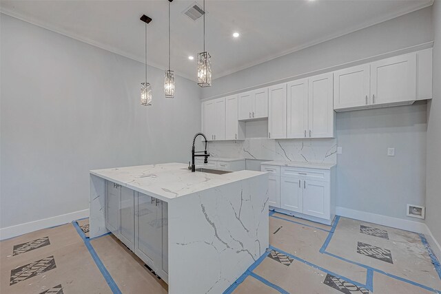 kitchen with backsplash, decorative light fixtures, white cabinetry, and a kitchen island with sink