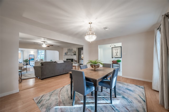 dining area with light hardwood / wood-style floors and ceiling fan with notable chandelier