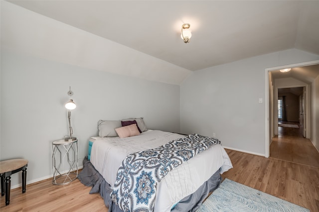 bedroom with vaulted ceiling and hardwood / wood-style flooring