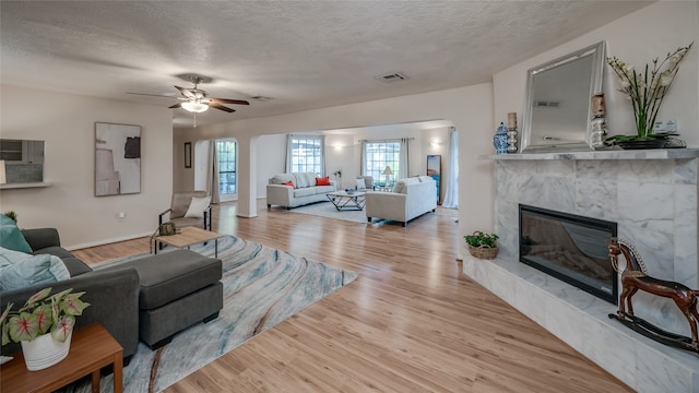 living room with a fireplace, a textured ceiling, and light wood-type flooring