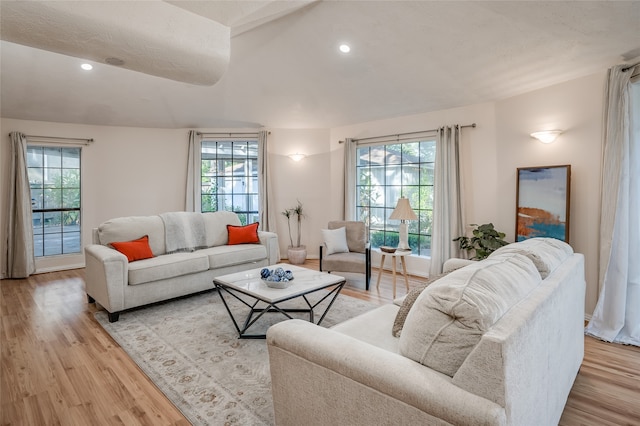 living room featuring vaulted ceiling, light hardwood / wood-style floors, and a healthy amount of sunlight