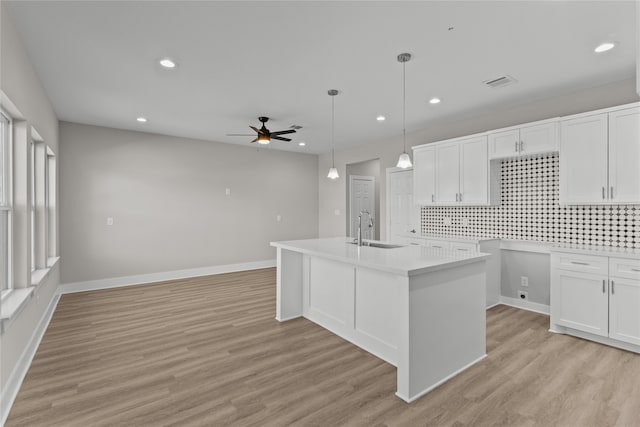 kitchen with white cabinetry, backsplash, sink, and light wood-type flooring