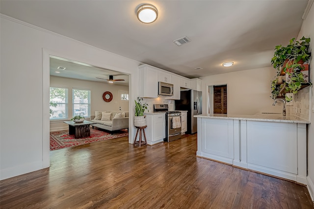 kitchen with white cabinets, tasteful backsplash, stainless steel appliances, and dark wood-type flooring