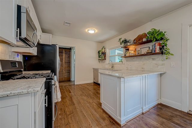 kitchen featuring light stone countertops, light wood-type flooring, backsplash, white cabinetry, and stainless steel appliances