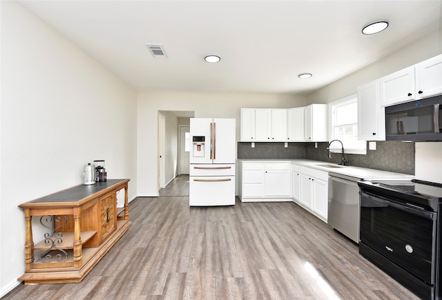 kitchen featuring black appliances, sink, light wood-type flooring, white cabinets, and decorative backsplash