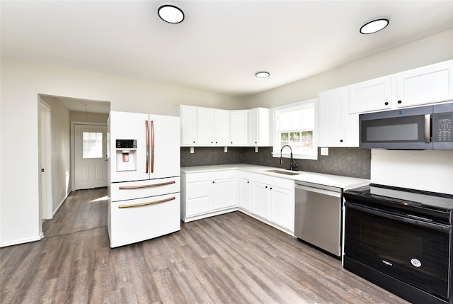 kitchen featuring appliances with stainless steel finishes, sink, white cabinetry, hardwood / wood-style flooring, and decorative backsplash