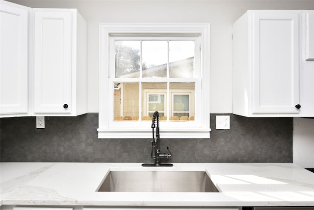 kitchen featuring white cabinetry, light stone counters, sink, and backsplash