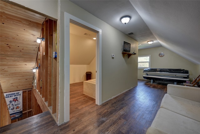 additional living space with wood walls, lofted ceiling, and dark hardwood / wood-style flooring