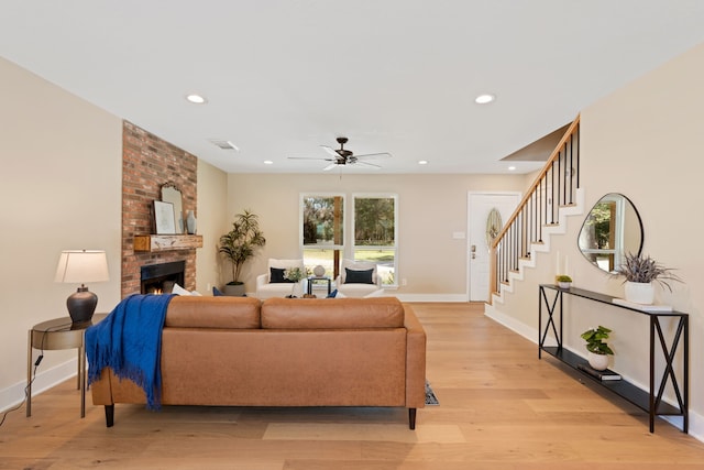 living room with ceiling fan, light hardwood / wood-style flooring, and a brick fireplace