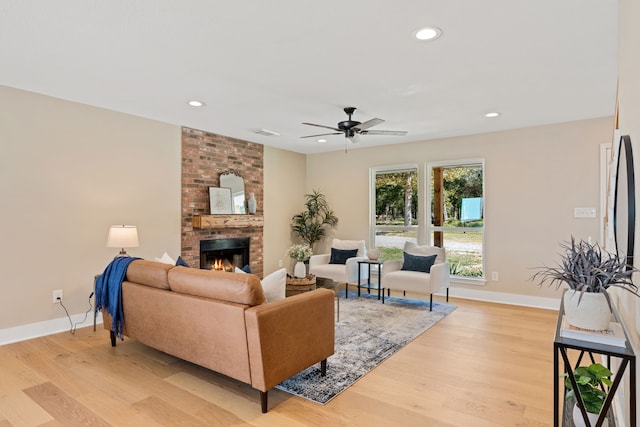 living room featuring a fireplace, light hardwood / wood-style floors, and ceiling fan