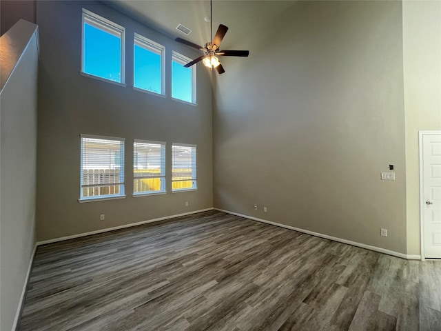 unfurnished room with dark hardwood / wood-style flooring, a healthy amount of sunlight, and a high ceiling