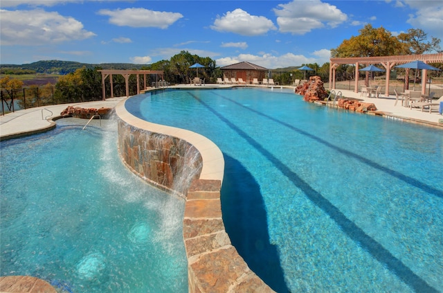 view of swimming pool featuring pool water feature, a patio, and a pergola