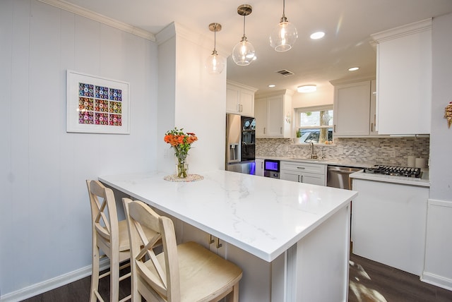 kitchen featuring pendant lighting, dark hardwood / wood-style floors, light stone counters, white cabinetry, and stainless steel appliances