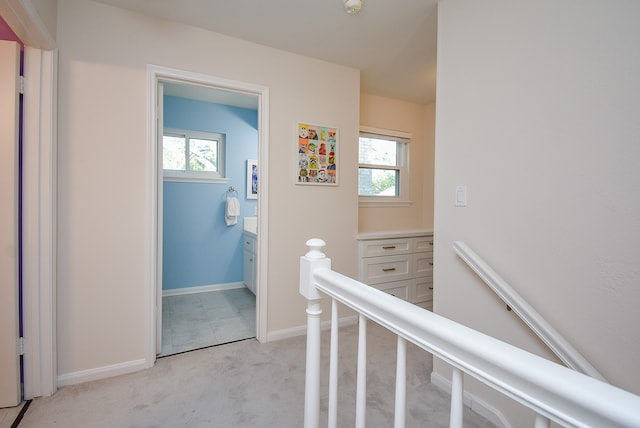 corridor featuring light colored carpet and plenty of natural light