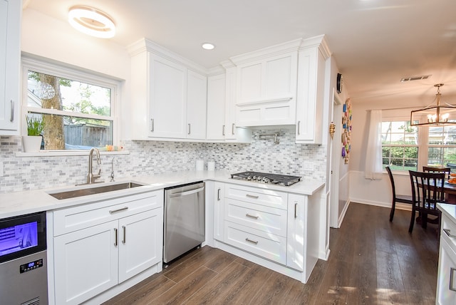 kitchen with backsplash, an inviting chandelier, white cabinets, sink, and stainless steel appliances