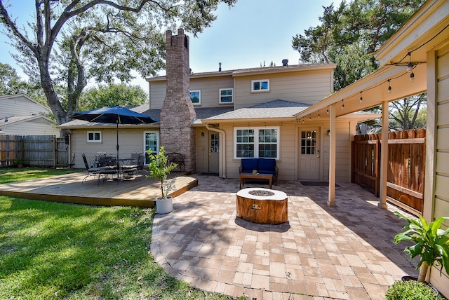 rear view of house featuring a deck and an outdoor fire pit