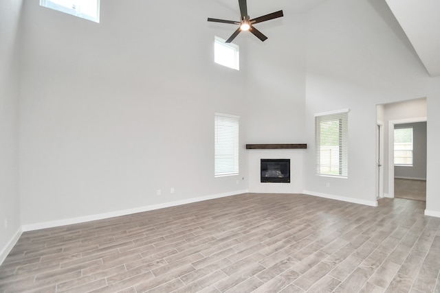 unfurnished living room featuring ceiling fan, high vaulted ceiling, and light wood-type flooring