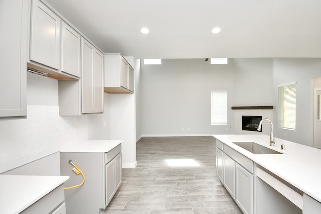 kitchen with tasteful backsplash, white dishwasher, light wood-type flooring, gray cabinets, and sink