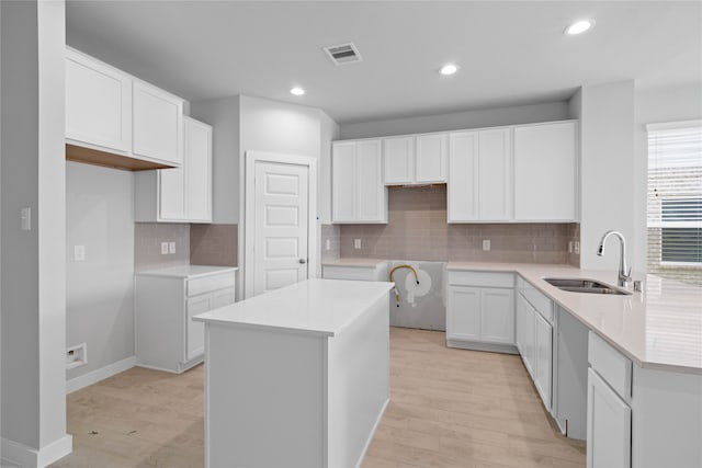 kitchen featuring tasteful backsplash, white cabinets, sink, and light hardwood / wood-style flooring