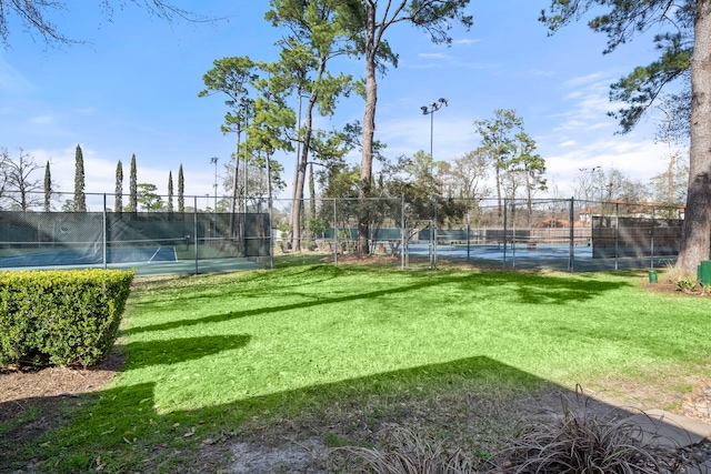 view of tennis court featuring a lawn