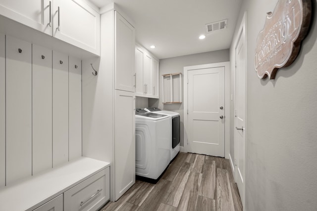 laundry room featuring washer and dryer, cabinets, and hardwood / wood-style floors