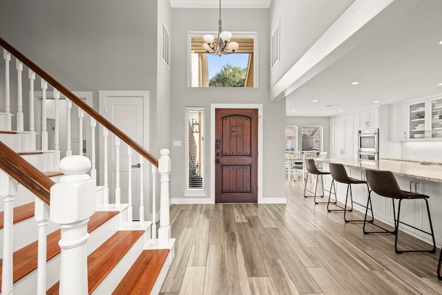 entryway featuring a high ceiling, a notable chandelier, and light wood-type flooring