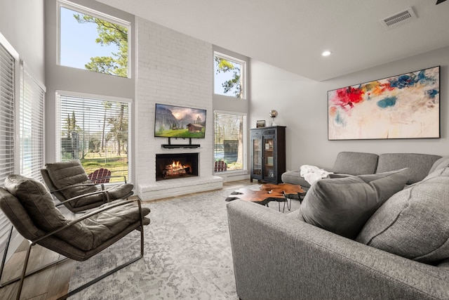 living room with a healthy amount of sunlight, a high ceiling, and a brick fireplace