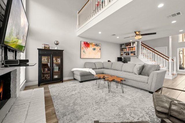 living room with light hardwood / wood-style flooring, a fireplace, and ceiling fan