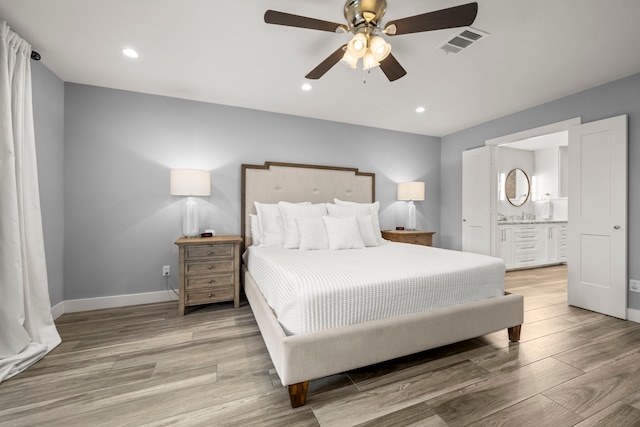 bedroom featuring connected bathroom, light hardwood / wood-style floors, and ceiling fan