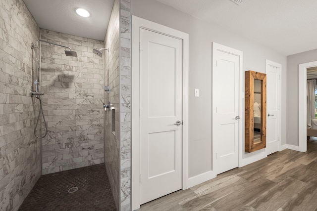 bathroom with tiled shower, a textured ceiling, and hardwood / wood-style flooring