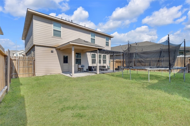 back of house with a patio area, a yard, and a trampoline