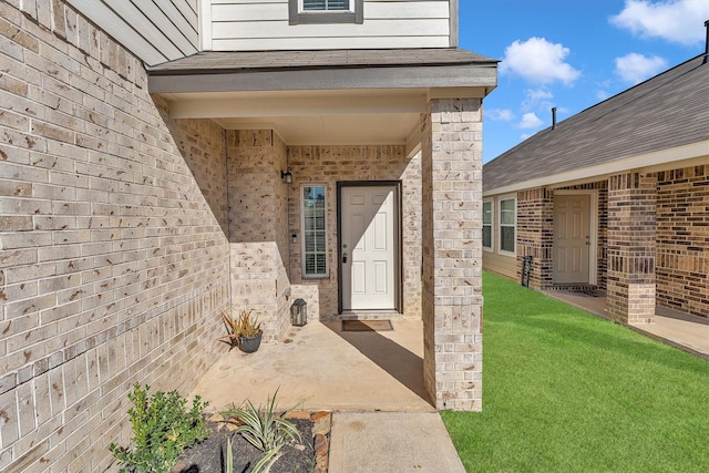 view of exterior entry featuring a lawn