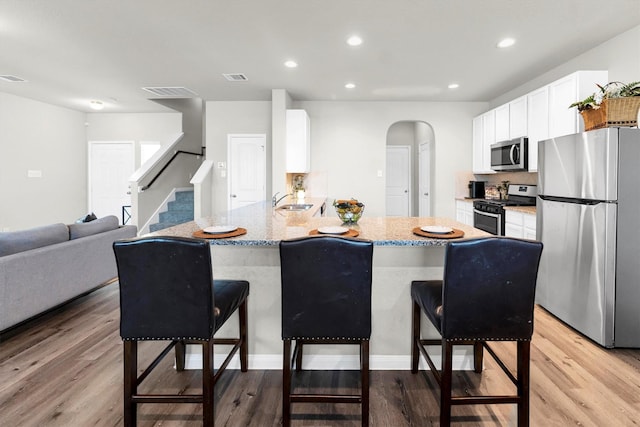 kitchen with kitchen peninsula, appliances with stainless steel finishes, sink, and a breakfast bar area